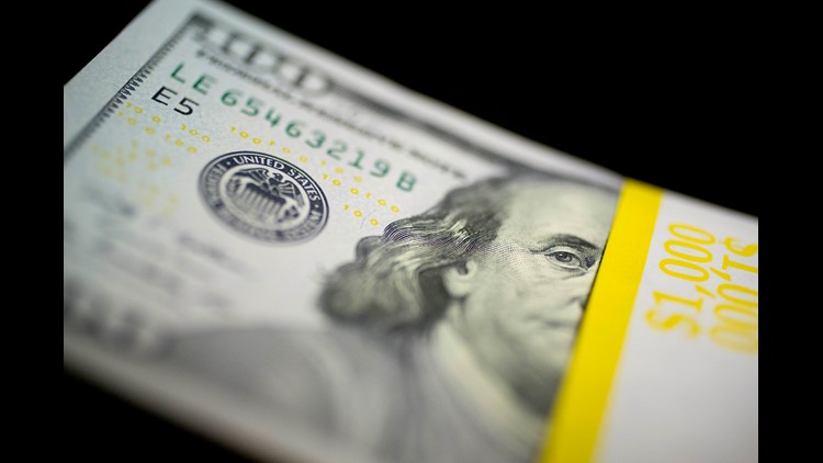 $100 bill sits on a stack of currency in this arranged photo