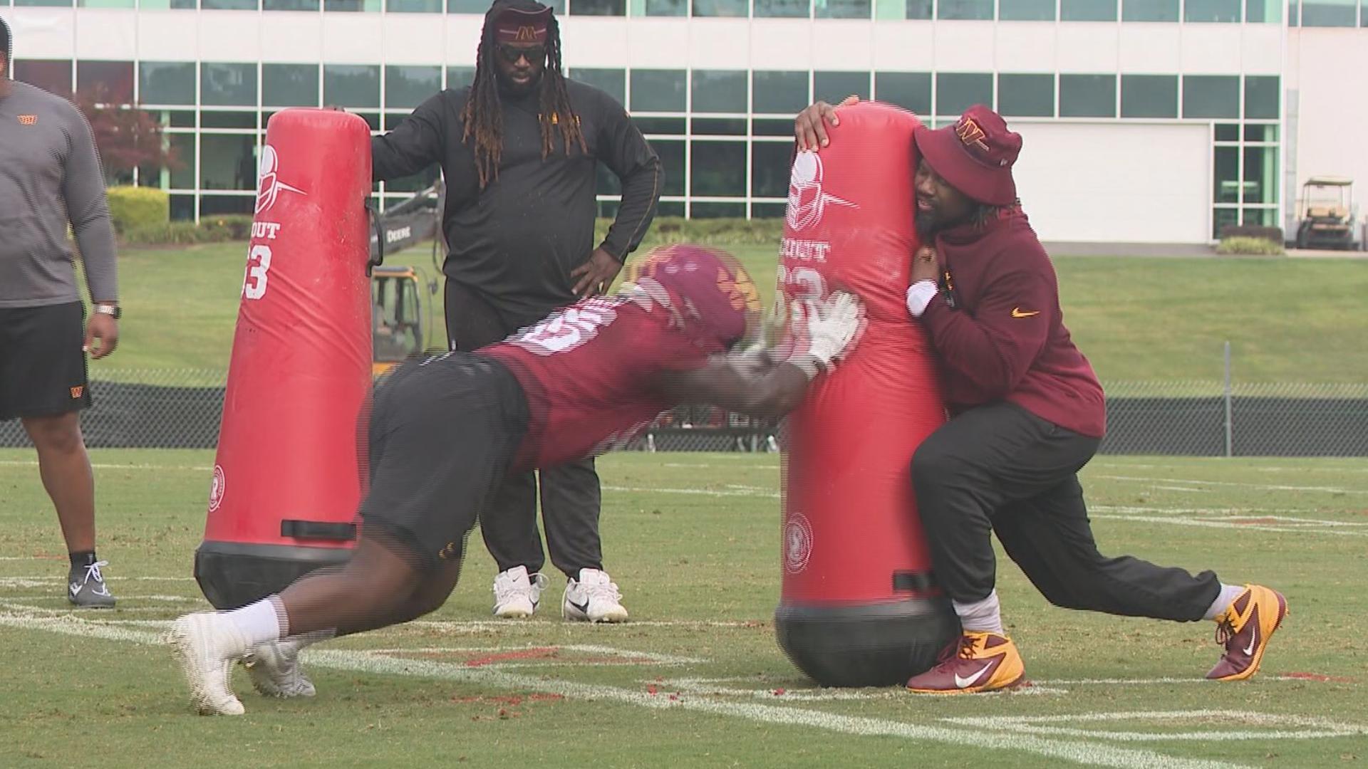 Commanders defensive line coach Darryl Tapp working with fellow Va. Tech Hokie Norell Pollard during training camp.