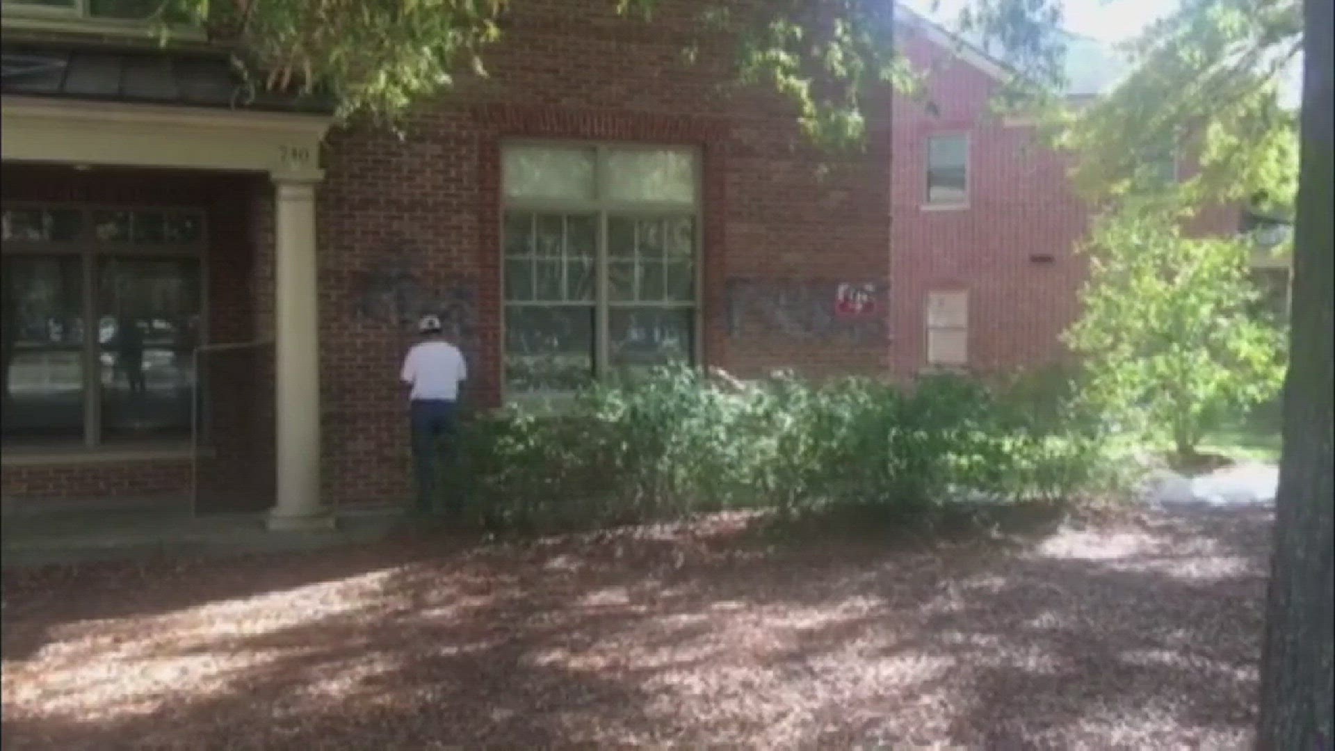 Crews remove graffiti that was spray-painted onto fraternity houses at the College of William & Mary.