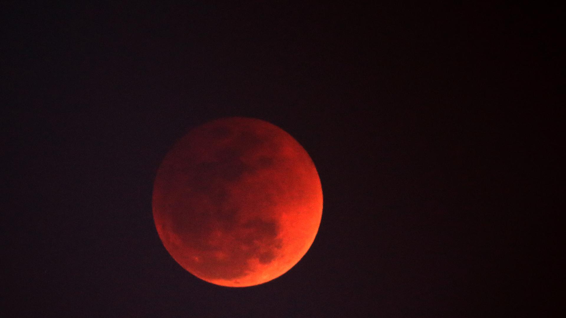 A lunar eclipse occurs when Earth blocks sunlight, casting a shadow on the Moon. The Moon appears red due to Earth's atmosphere filtering out blue light.